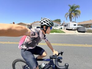 Reviewer riding a road bike in Slowtwitch kit while wearing the H2O Audio TRI Run open-ear bone conduction headphones.